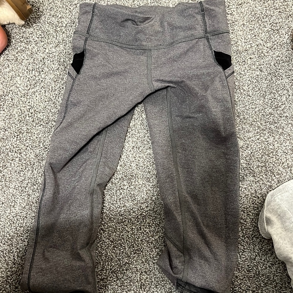 ivivva gray capri leggings with a blue triangle designs on the side.